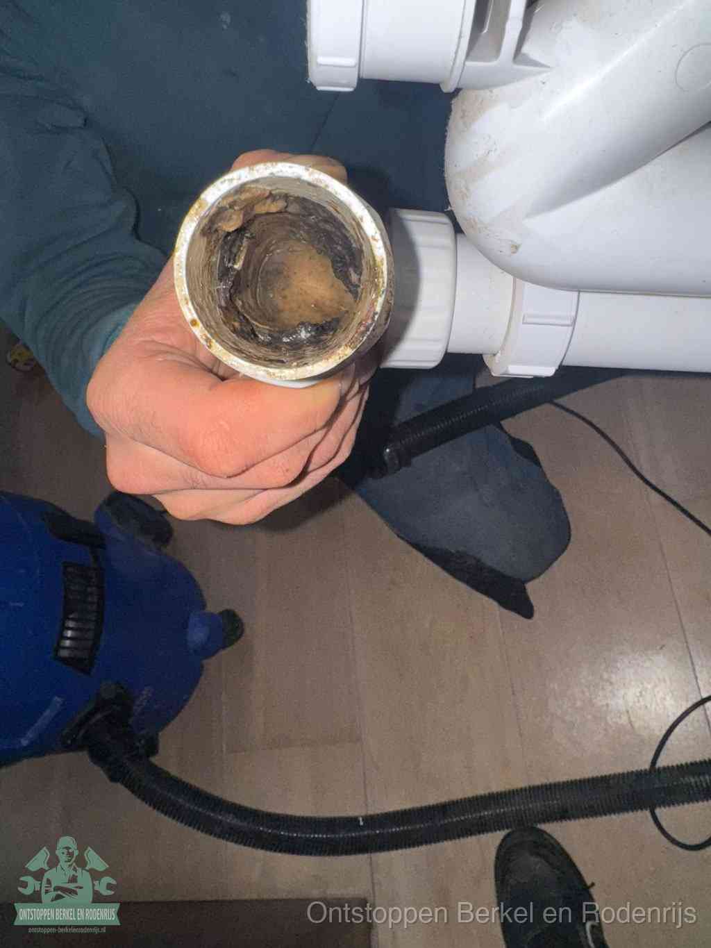 Een losgekoppelde afvoerbuis die van binnen volledig is dichtgeslibd met vet en aanslag, de meest voorkomende oorzaak van een verstopte gootsteen in Berkel en Rodenrijs
