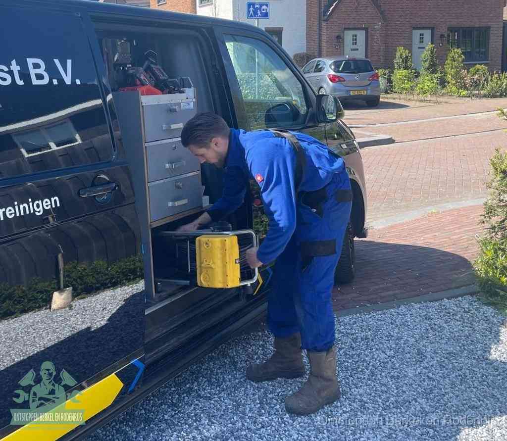 Een monteur pakt buiten op de oprit gereedschap uit de bedrijfsbus, het moment om een professional in te schakelen voor een verstopte afvoer in Berkel en Rodenrijs
