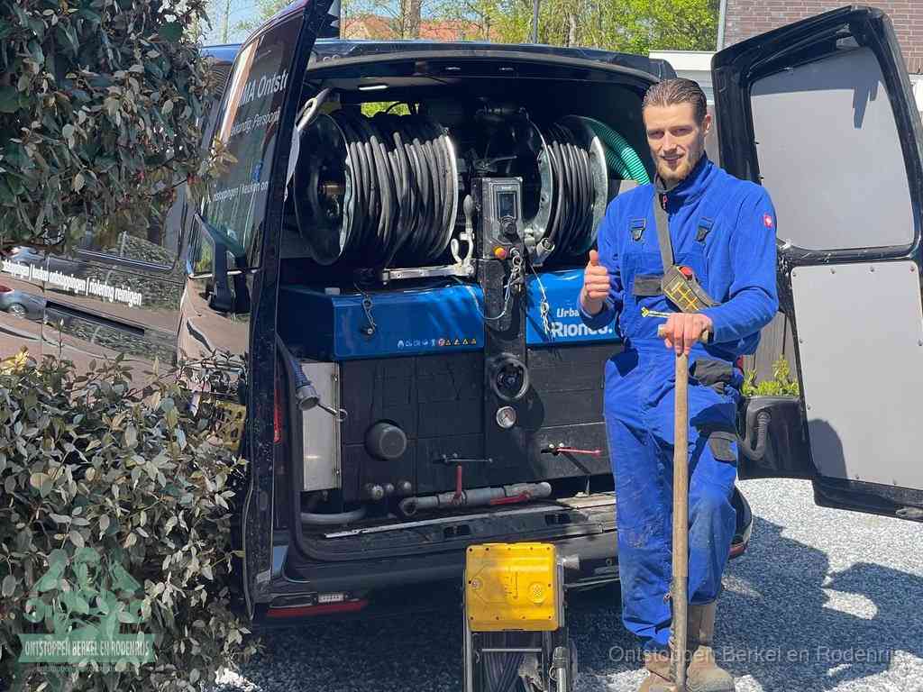 Lachende monteur bij de volle rioolreinigingsbus, een professioneel rioolontstoppingsbedrijf in Berkel en Rodenrijs