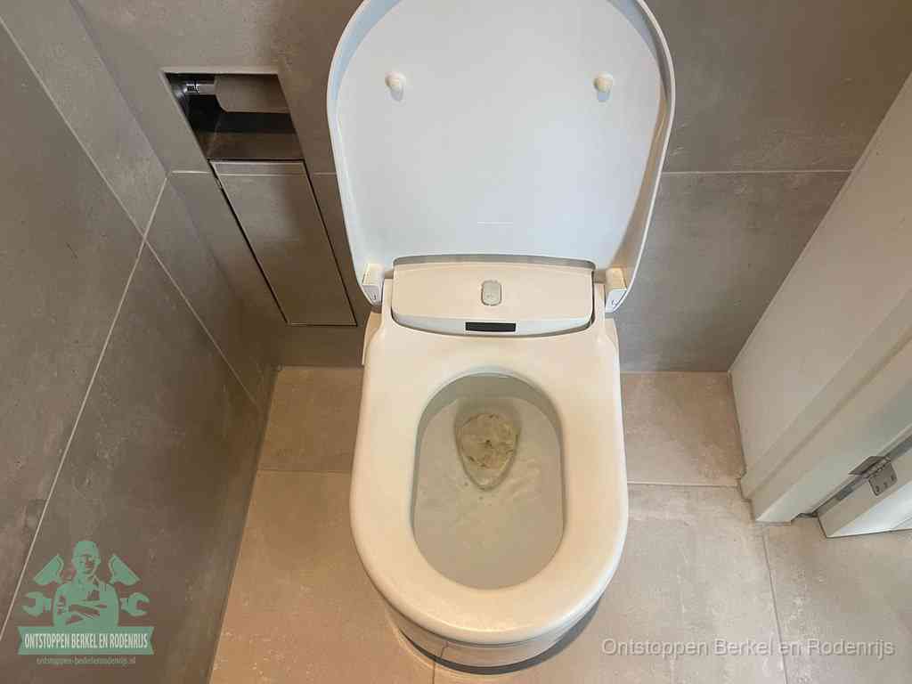 Een wit hangtoilet waarin een prop wc-papier op het water blijft drijven, een duidelijk signaal van een verstopte wc in Berkel en Rodenrijs
