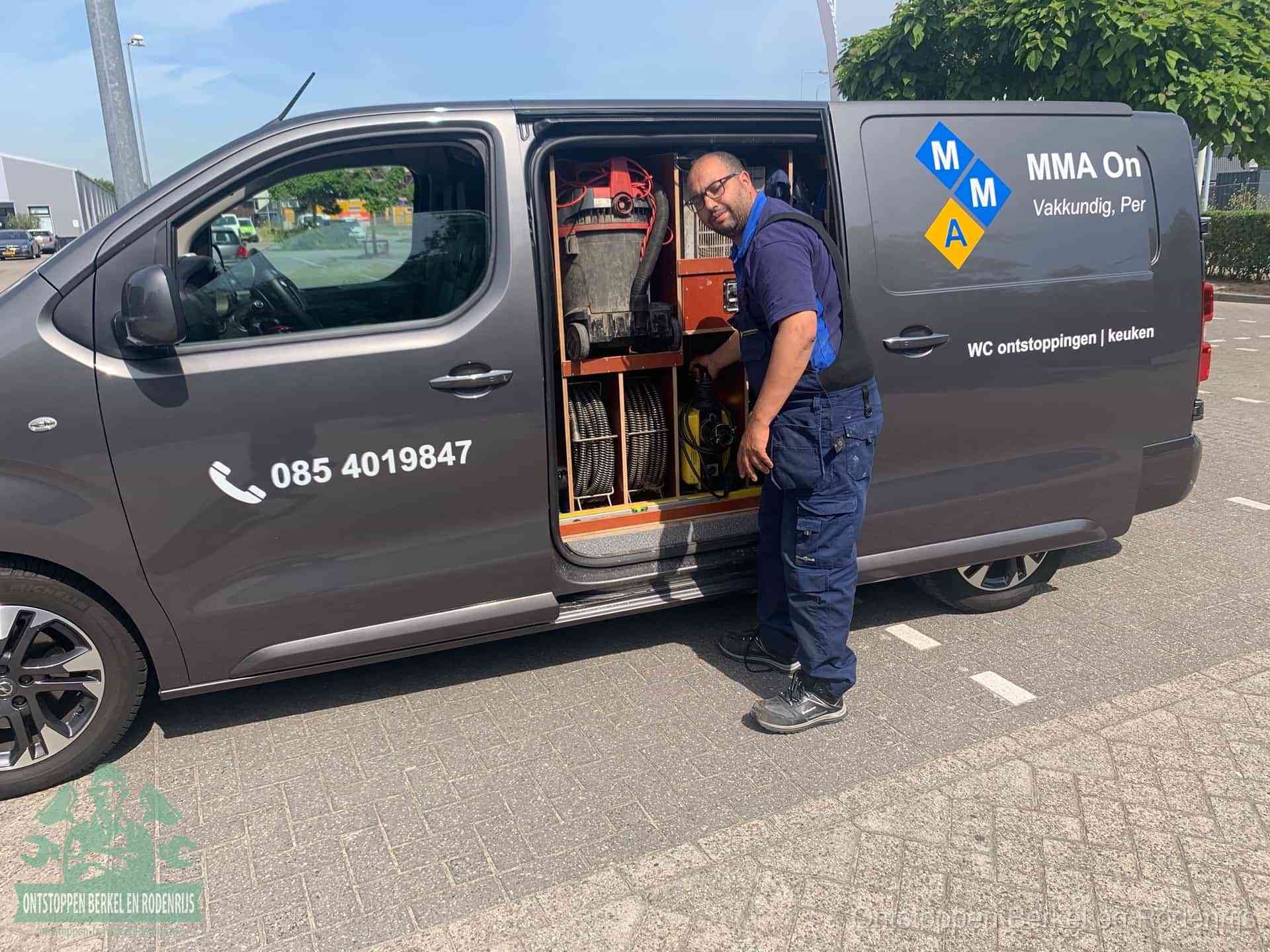 Een monteur bij de open schuifdeur van zijn bedrijfsbus op een parkeerplaats, klaar om de oorzaak van terugkerende afvoerverstoppingen aan te pakken in Berkel en Rodenrijs