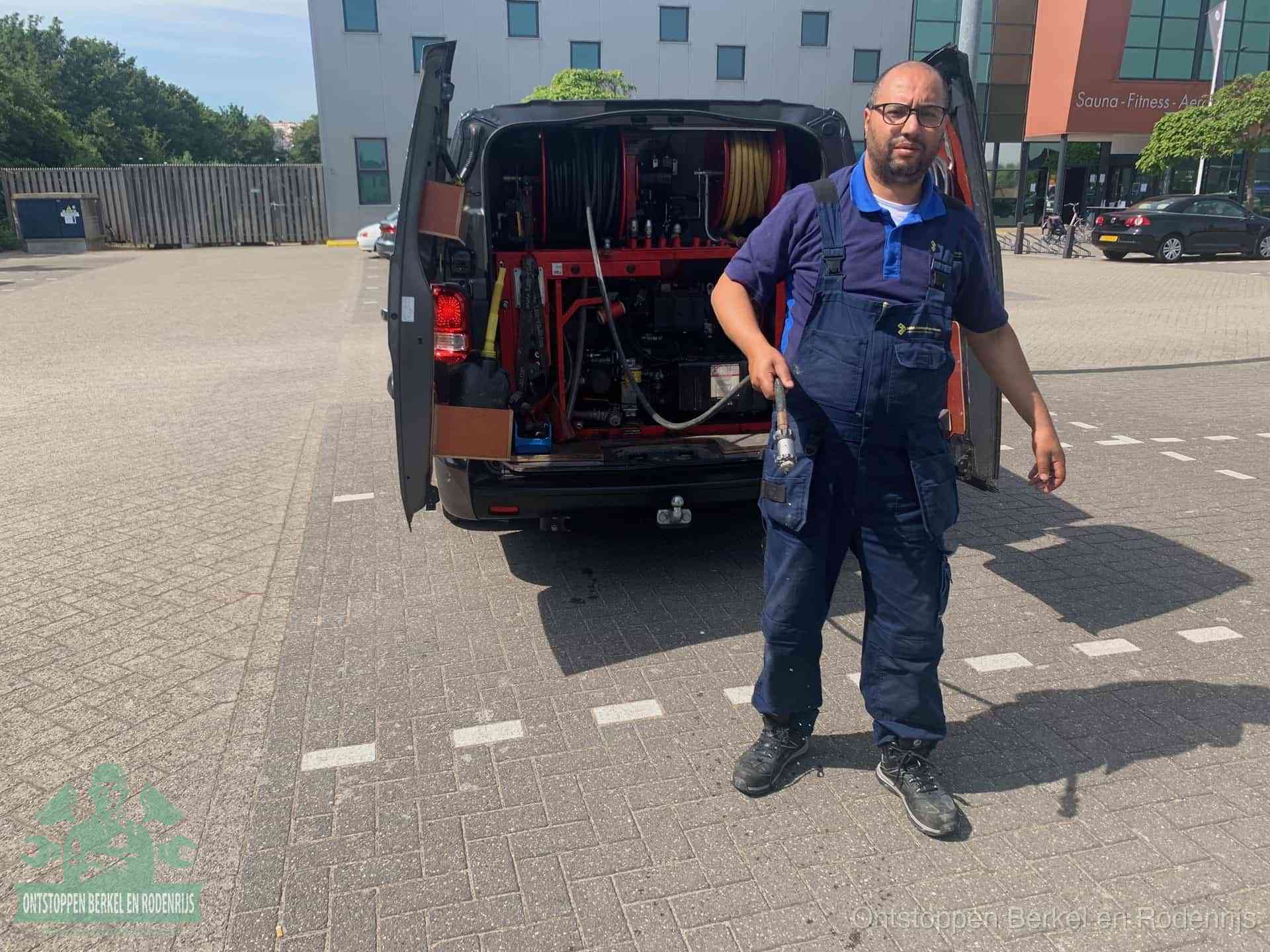 Een monteur bij zijn bestelbus met een hogedruk- en rioolreinigingsunit, klaar om de oorzaak van terugkerende wc-verstoppingen aan te pakken in Berkel en Rodenrijs
