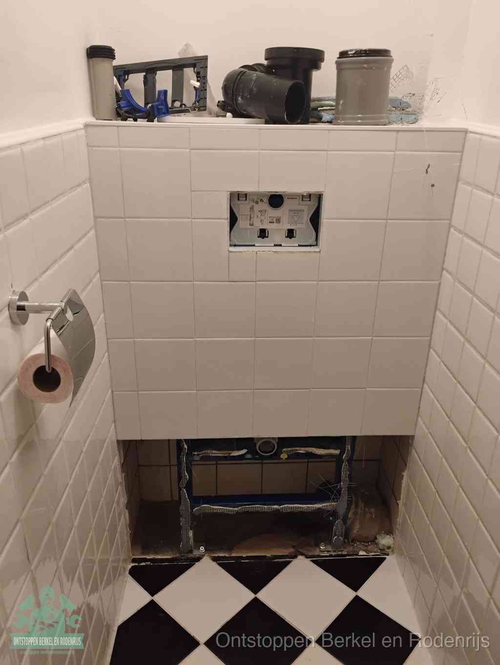 Een toiletruimte waar het hangtoilet en de inbouwreservoir-onderdelen zijn vrijgelegd voor onderhoud, periodiek nazicht voorkomt een wc-verstopping in Berkel en Rodenrijs